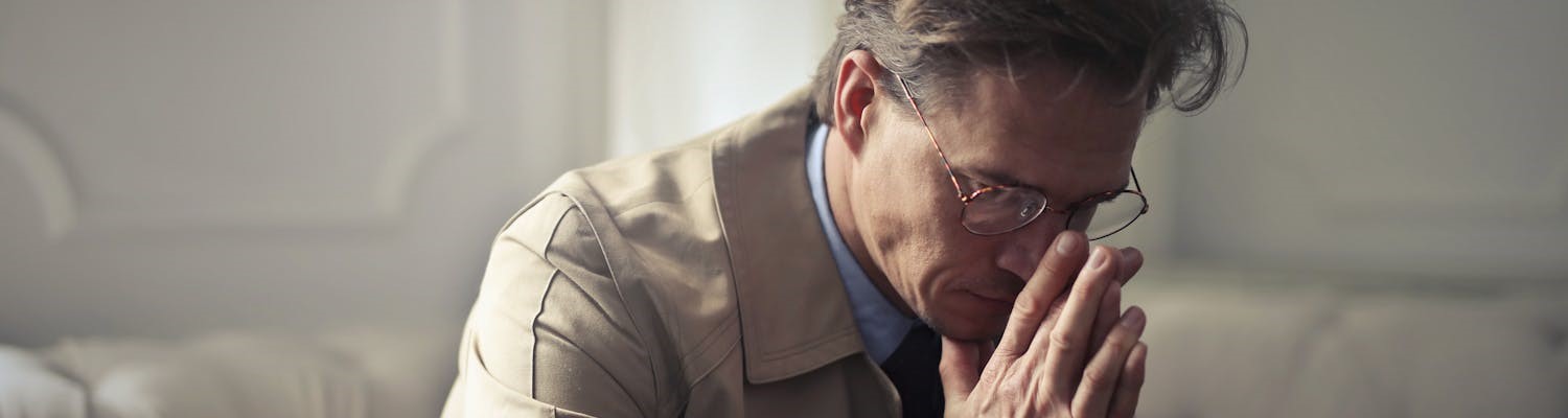 a worried man with glasses, thinking about the risks of Alcohol Detox at Home