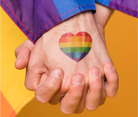 A pride flag heart on two holding hands for Pride Month